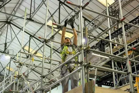 Worker assembling scaffolding indoors