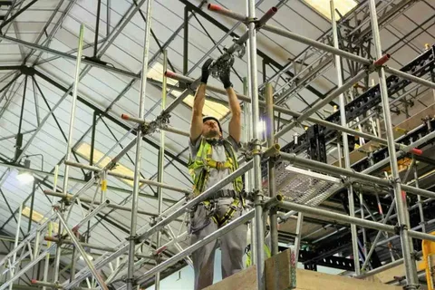 Worker assembling scaffolding indoors