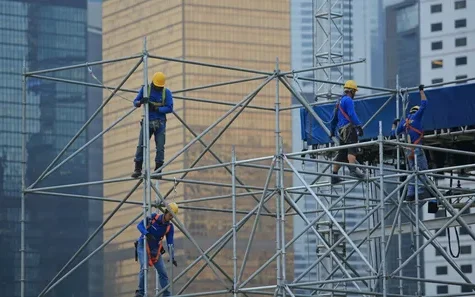 Workers assembling scaffolding at a high rise construction site
