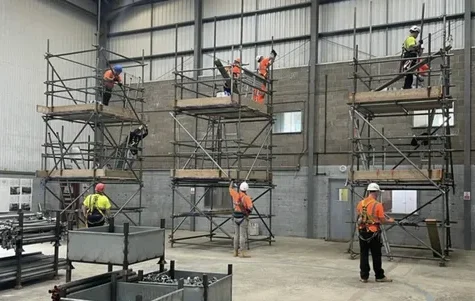 Workers training on scaffold towers in an indoor facility