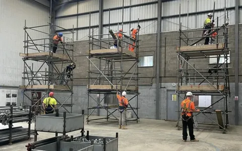 Workers training on scaffold towers in an indoor facility