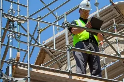 Construction worker inspecting scaffolding with a clipboard