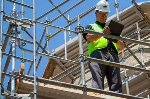 Construction worker inspecting scaffolding with a clipboard