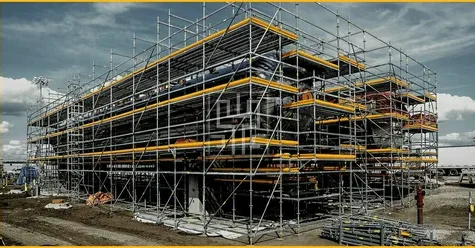 Industrial building fully surrounded by multi-level scaffolding during construction.