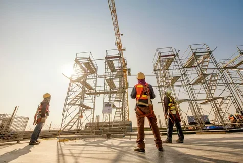 Construction workers in safety gear standing near scaffolding structure.