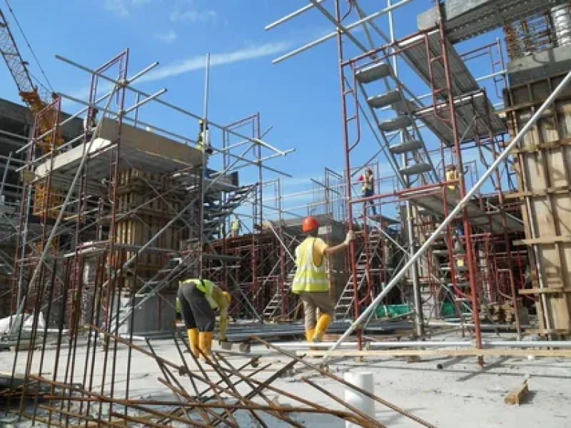 Construction workers assembling scaffolding on a building site.