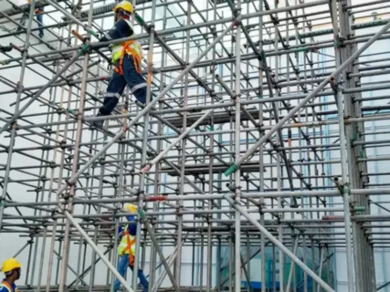 Workers assembling large steel scaffolding on-site
